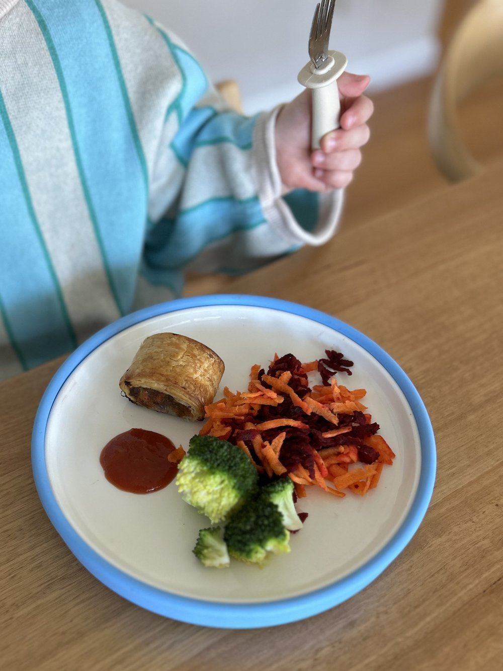 A child sharing a family mealtime with a blue Plate Mate
